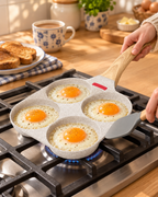 Four eggs frying in the Sunnyside 4-cup non-stick egg pan on a hob